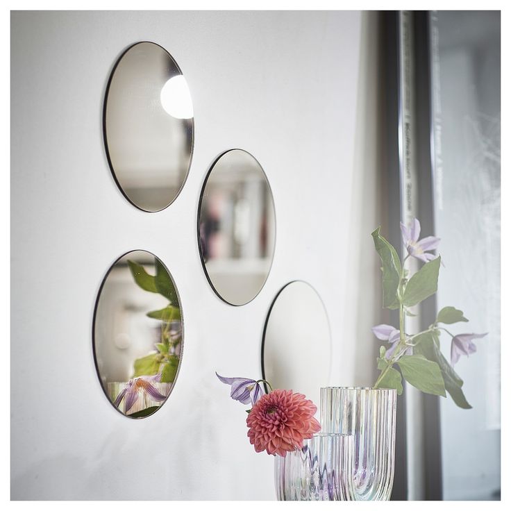 three circular mirrors hanging on the wall above a vase with flowers in it and a pink flower