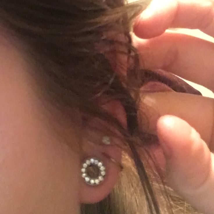 a close up of a person with ear piercings on their ears and hair in the wind