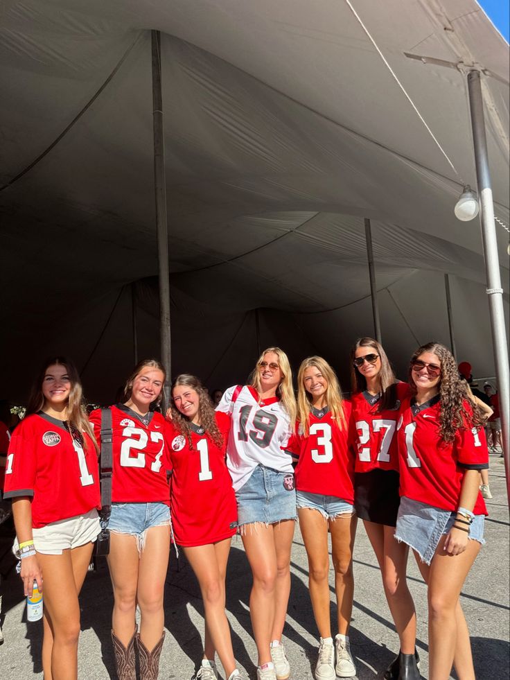 a group of young women standing next to each other in front of a white tent