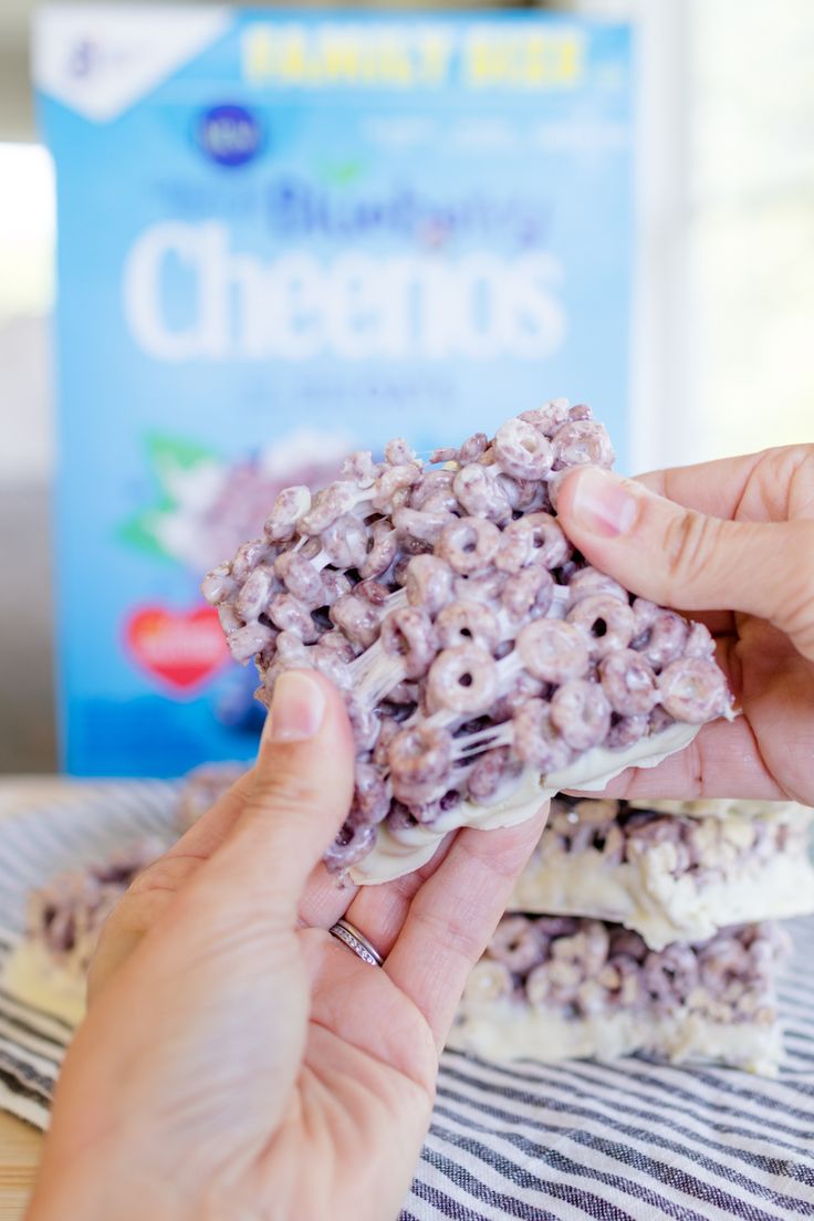 a person is holding up some cereals on a table next to a box of cereal