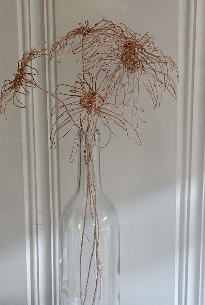 a clear glass vase with dried flowers in it sitting on a table next to a white wall