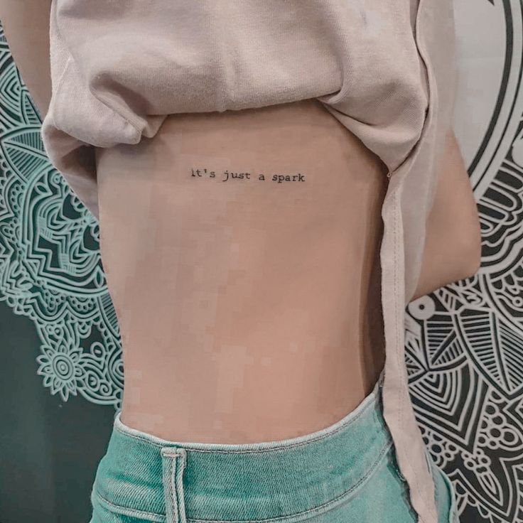 the back of a woman's stomach with an inscription on it that reads, it's just a spark