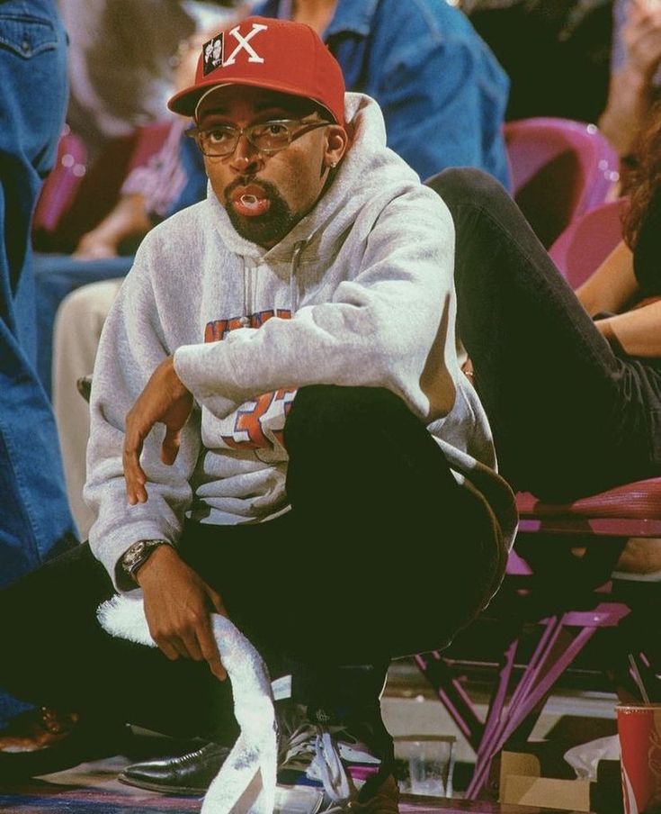 a man sitting on top of a chair wearing a red hat