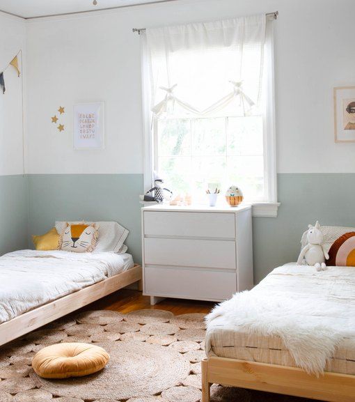 two twin beds in a bedroom with white walls and rugs on the wooden floor