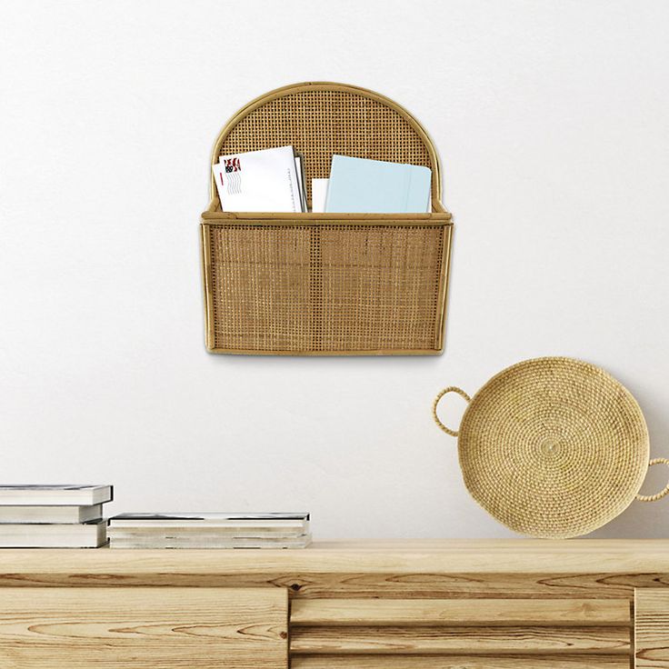 a wicker basket hanging on the wall next to a wooden dresser with books and magazines