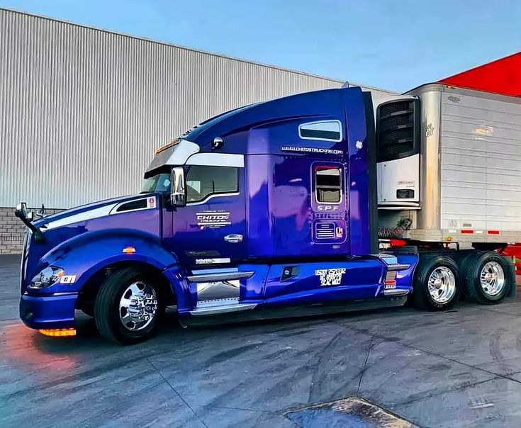 a blue semi truck parked in front of a building