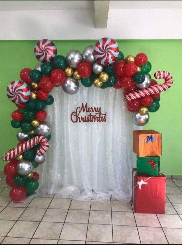 a christmas decoration made out of balloons and candy canes on the front of a green wall