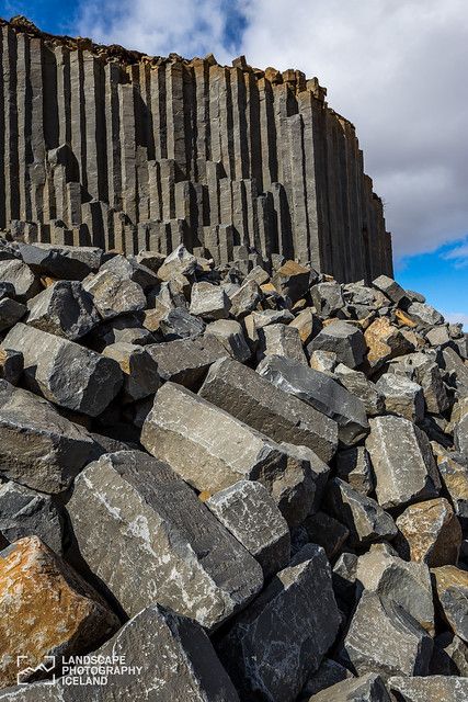 a large pile of rocks sitting on top of a beach next to a tall building