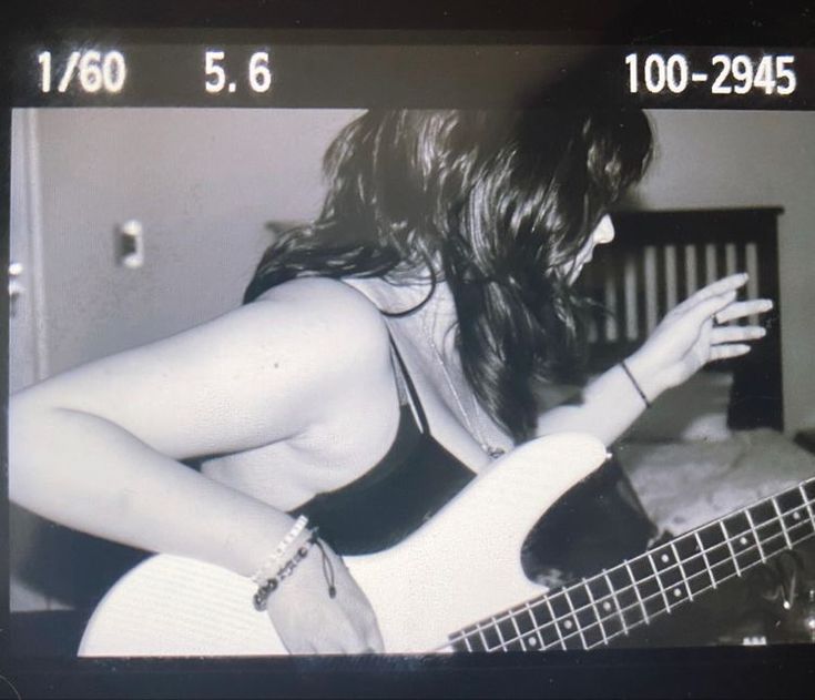 black and white photograph of a woman playing a bass guitar with her hands in the air