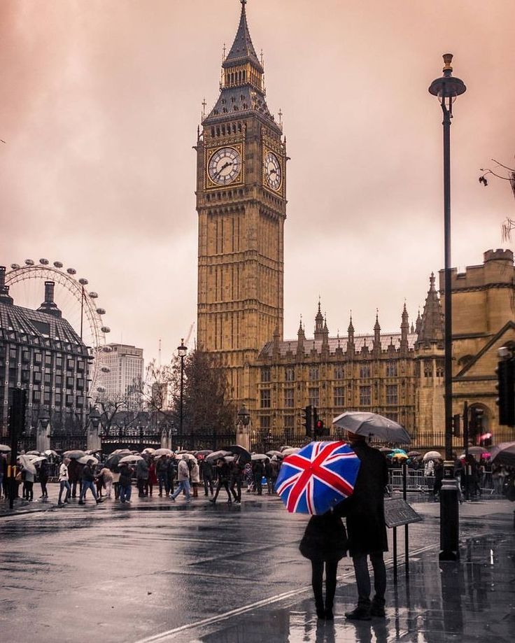 two people with umbrellas are standing in front of big ben