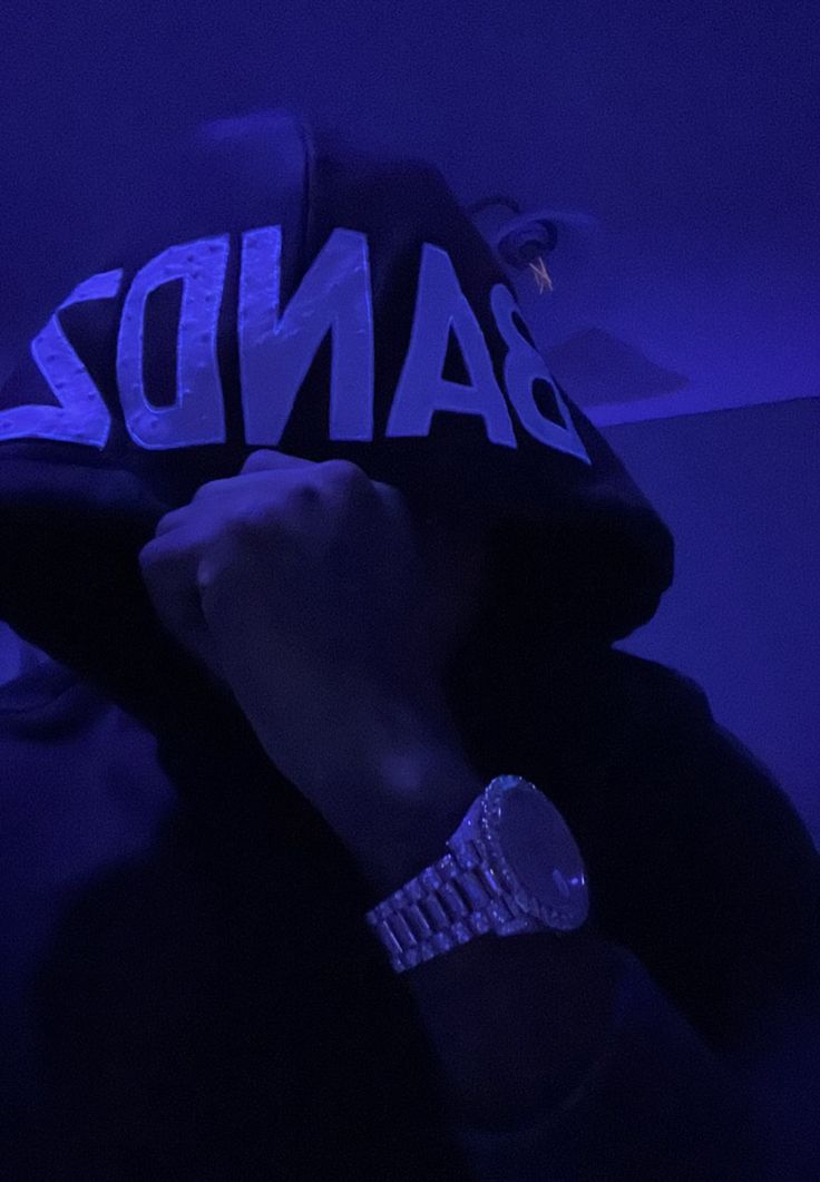 a person wearing a bandz hoodie in the dark with their hand on his face