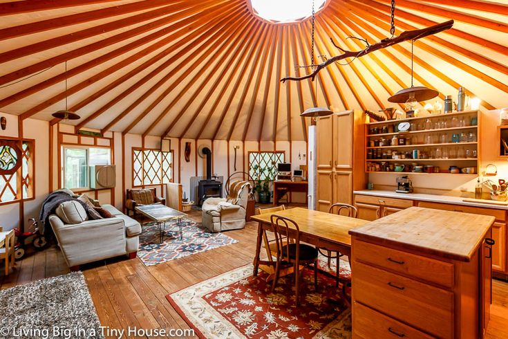 the inside of a yurt with wooden floors and walls, wood flooring, large round ceiling