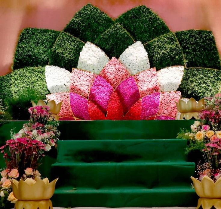 an arrangement of flowers and greenery on display in front of a green staircase case