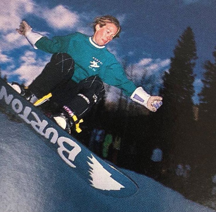 a man riding a snowboard down the side of a ramp in front of trees