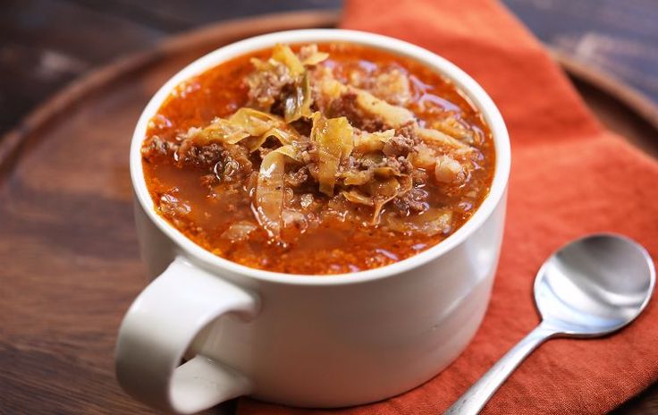 a white bowl filled with soup on top of a red napkin next to a spoon