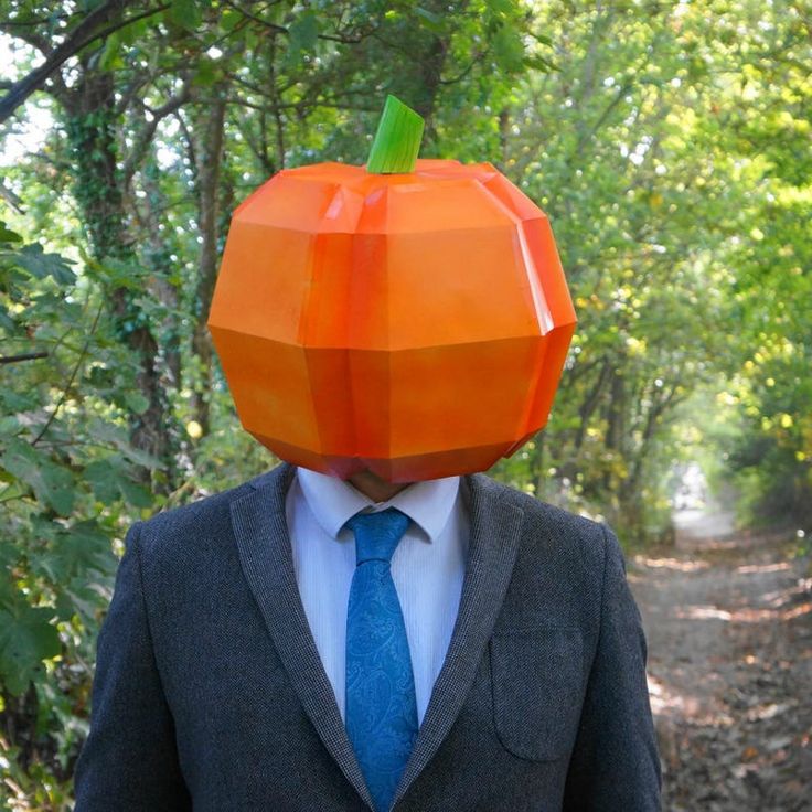 a man in a suit and tie wearing an orange paper pumpkin hat on his head