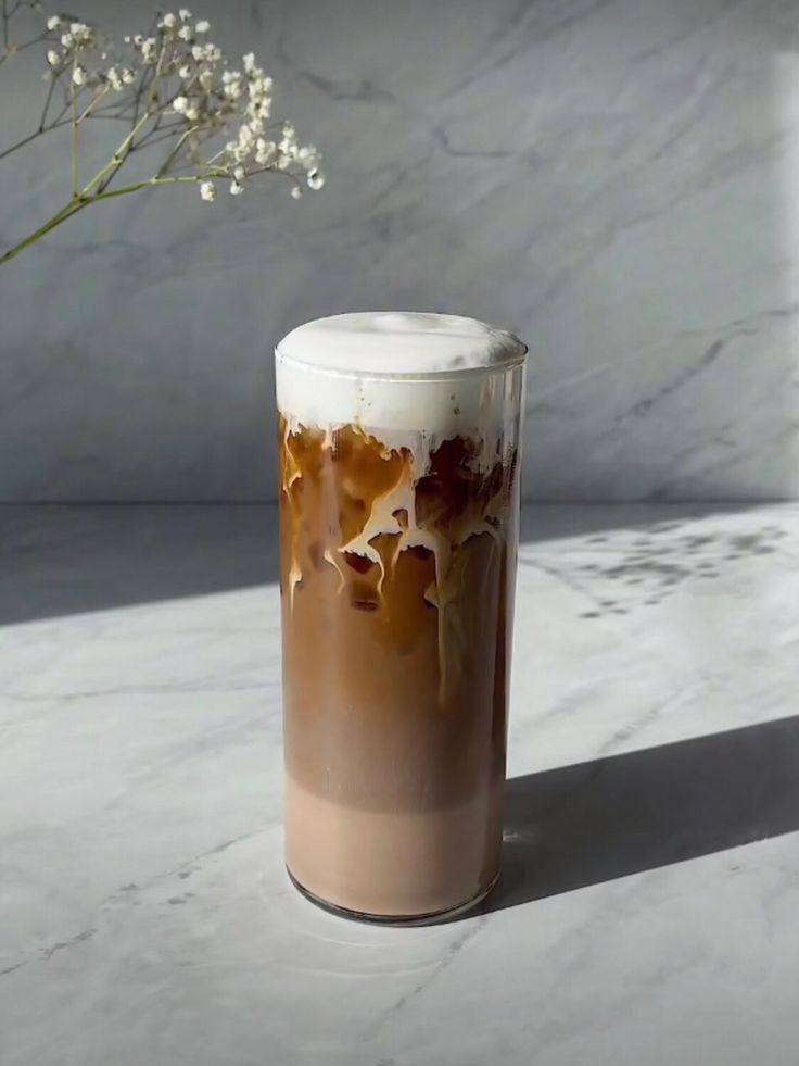 there is a vase with some flowers in it on the marble counter top next to a white wall