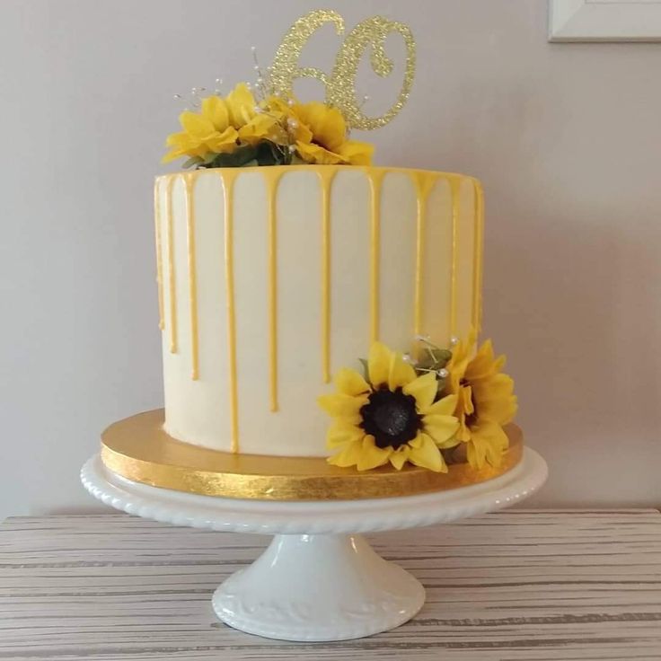 a white and yellow cake with sunflowers on the top is sitting on a table