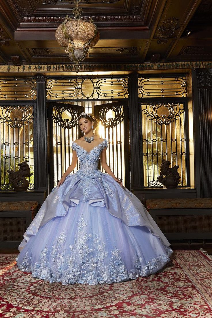 Fairytale vibe is this dazzling tulle quinceanera ballgown by Moirlee,89331. An elegant off-the-shoulder bodice accented by crystal beaded embroidery and cascading three-dimensional flowers! A unique touch of a drape, iridescent over skirt finishes off the gown. Perfect for your special day! Princesa Tiana, Quince Dress, Princess Sleeves, Iridescent Crystal, Mori Lee, Blush Dresses, Quince Dresses, Blush And Gold, Tulle Fabric