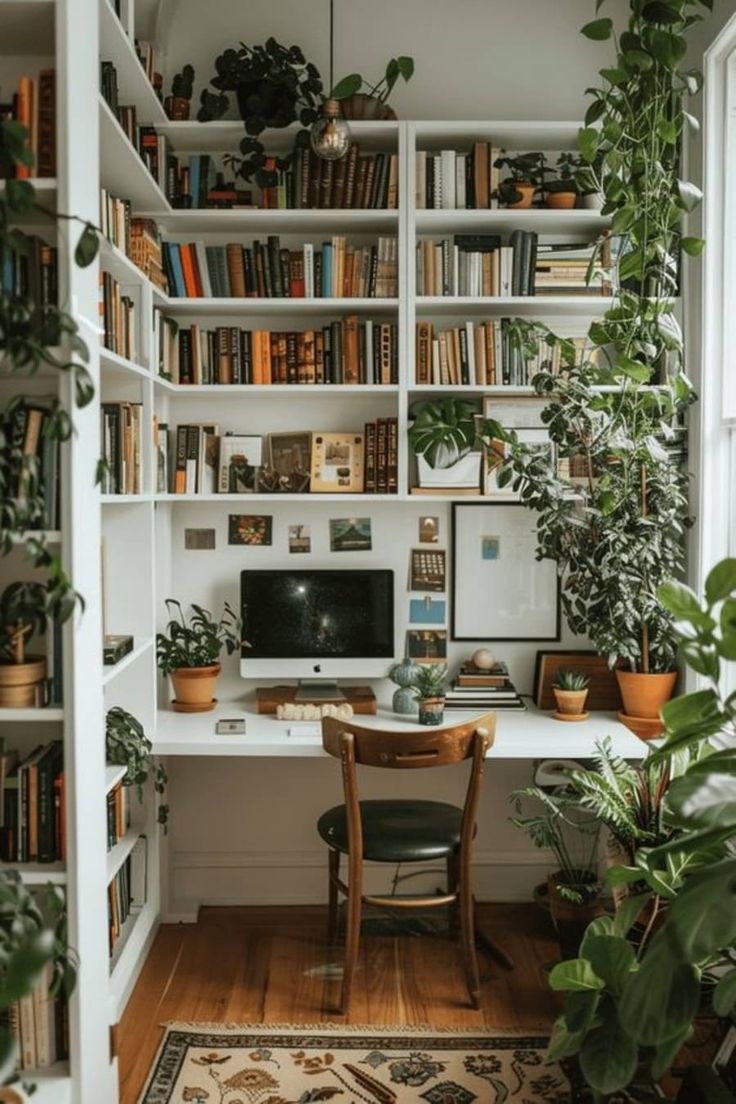 a home office with bookshelves, plants and a computer on a desk in the corner