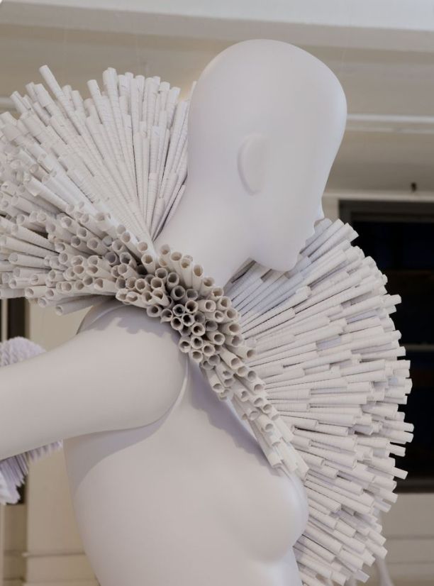 a white mannequin with many pieces of paper on it's head and arms