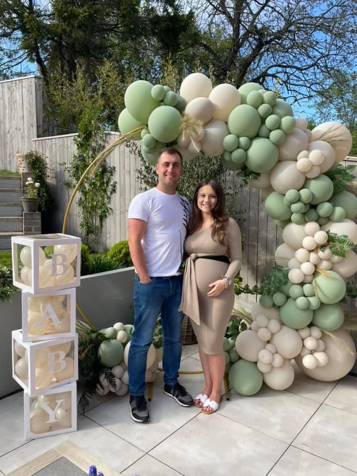 a man and woman standing next to each other in front of an arch made out of balloons