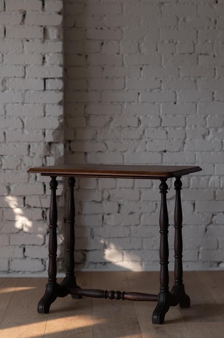 a wooden table sitting in front of a white brick wall on top of a hard wood floor