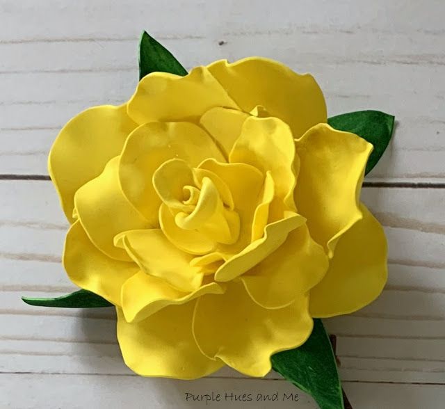 a yellow flower is sitting on a white surface