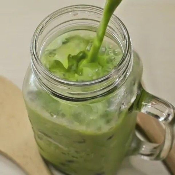 a green smoothie in a mason jar with a wooden spoon