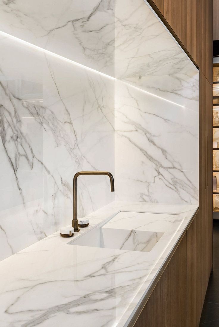 a kitchen with marble counter tops and gold faucets