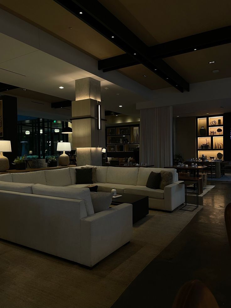 a living room with couches and lamps inside of it at night time in the dark