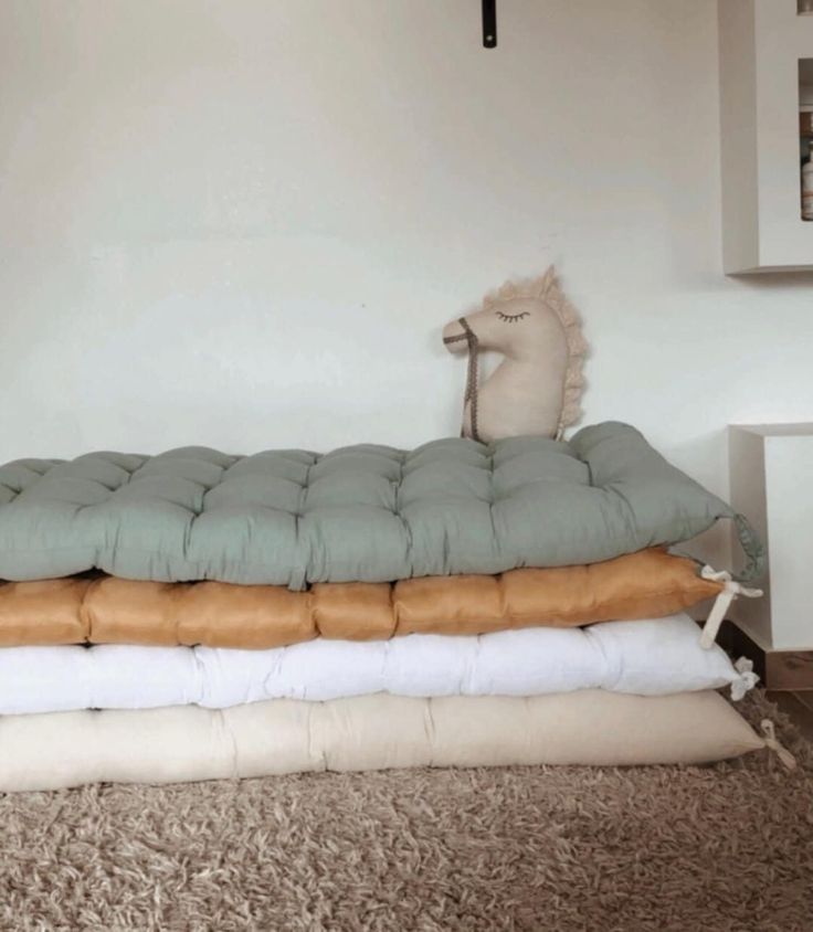 three pillows stacked on top of each other in front of a white wall and floor