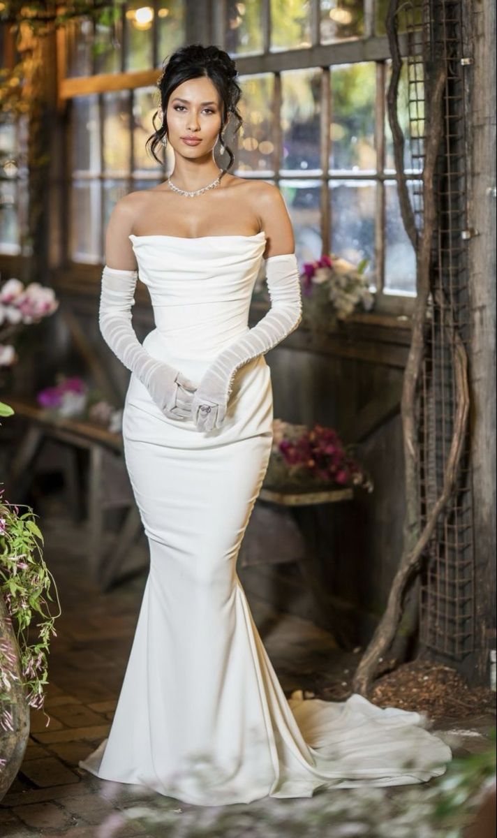 a woman in a white dress and gloves posing for the camera with her hands on her hips