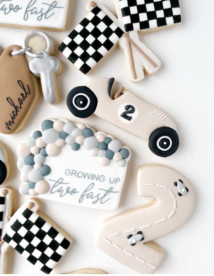 decorated cookies are arranged in the shape of race cars and checkered flags with words on them