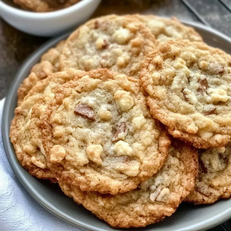 several cookies on a plate next to a bowl of oatmeal in the background