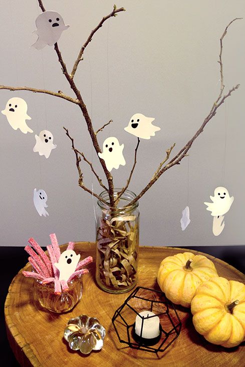 a wooden table topped with halloween decorations and branches in a mason jar filled with candy