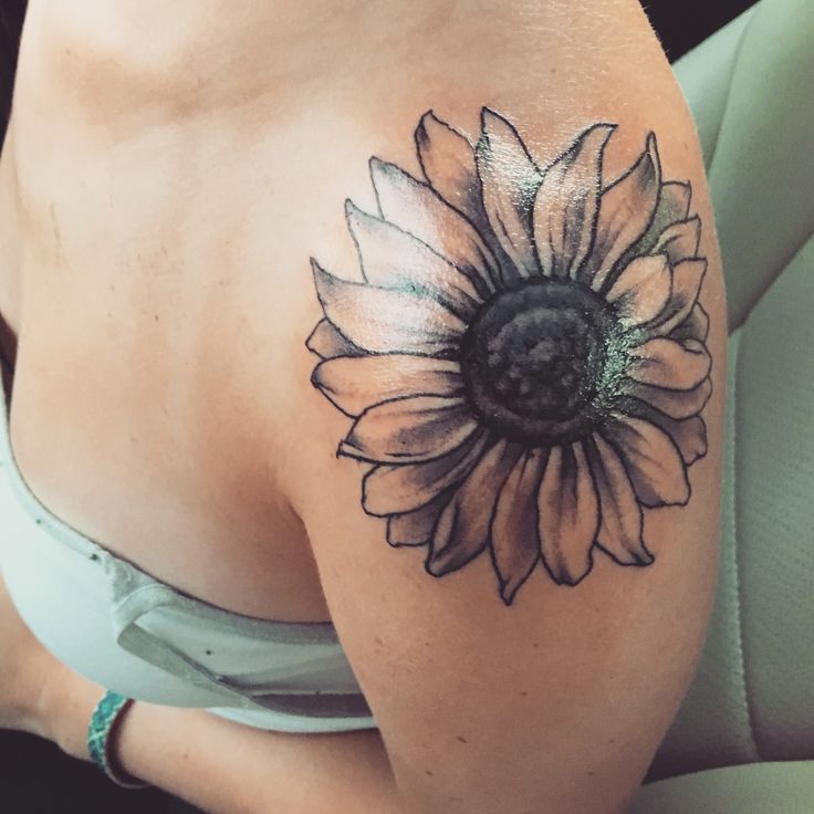 a sunflower tattoo on the back of a woman's left arm and shoulder