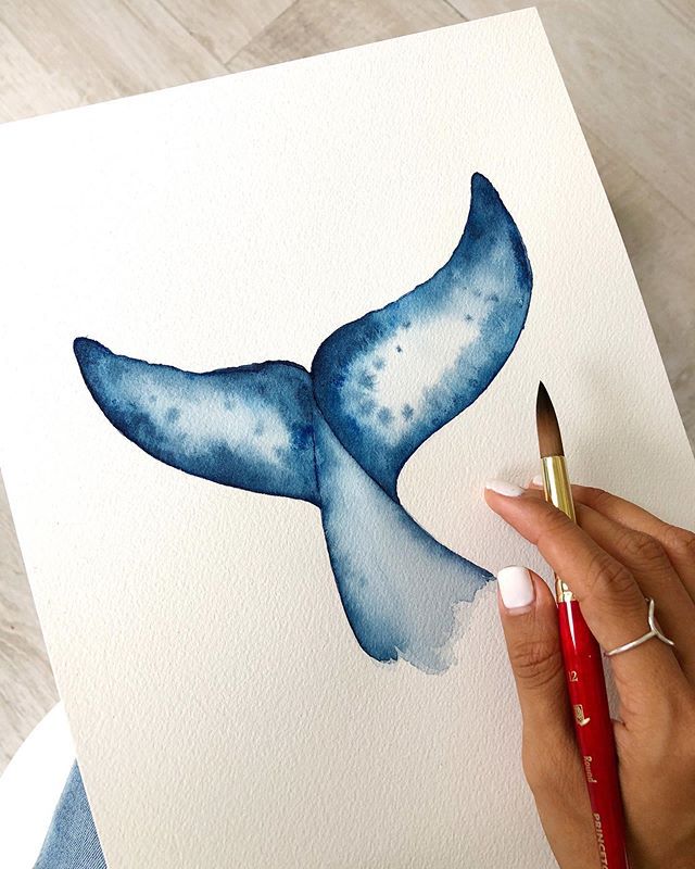 a watercolor painting of a blue whale tail on white paper with a red brush