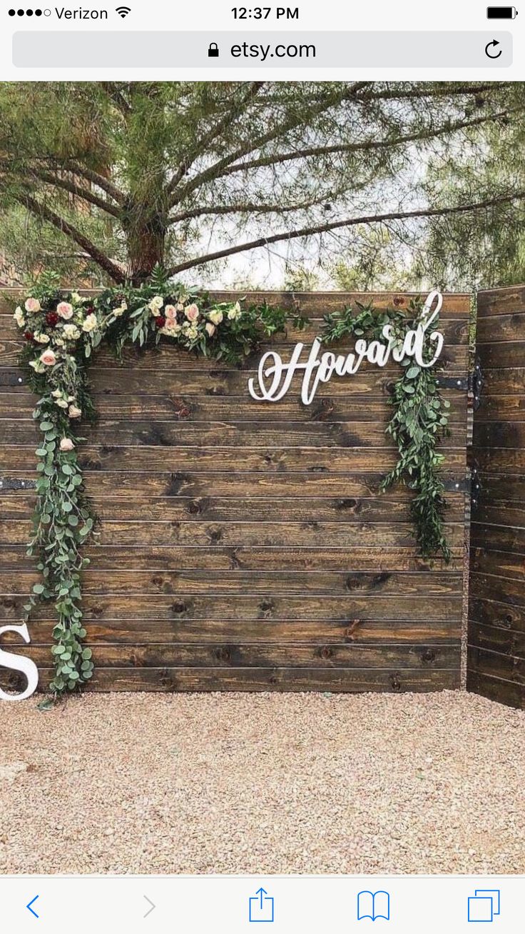 a wooden sign with flowers and greenery on it