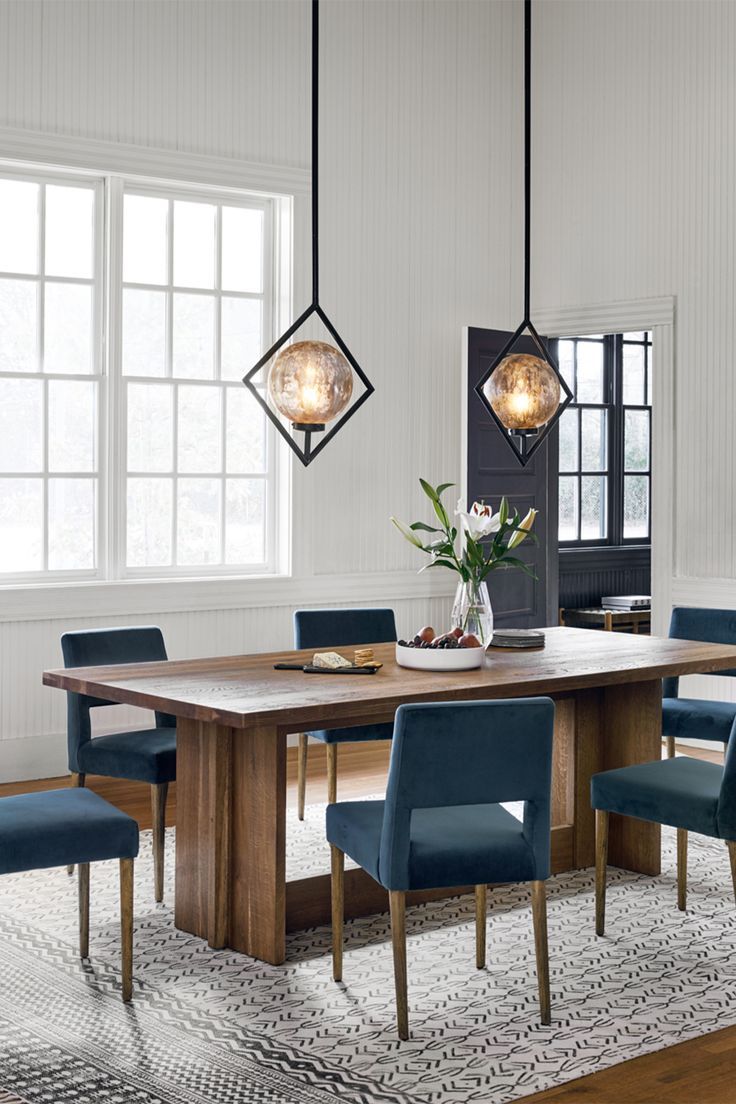 a dining room table with blue chairs and a potted plant