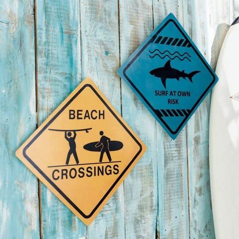 two signs on the side of a wooden wall next to a surfboard and board