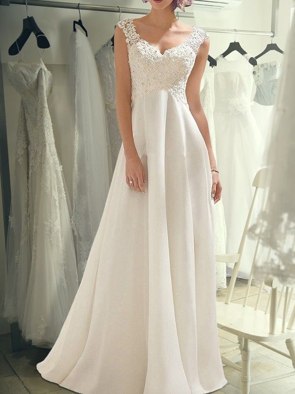 a woman is standing in front of some wedding gowns and dresses hanging on racks