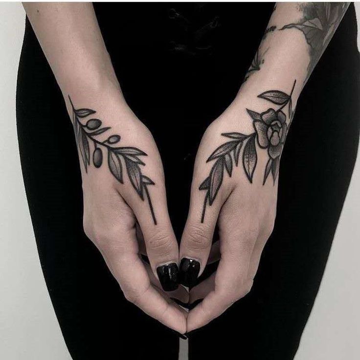 two hands with tattoos on them holding a knife in the shape of a flower and leaves