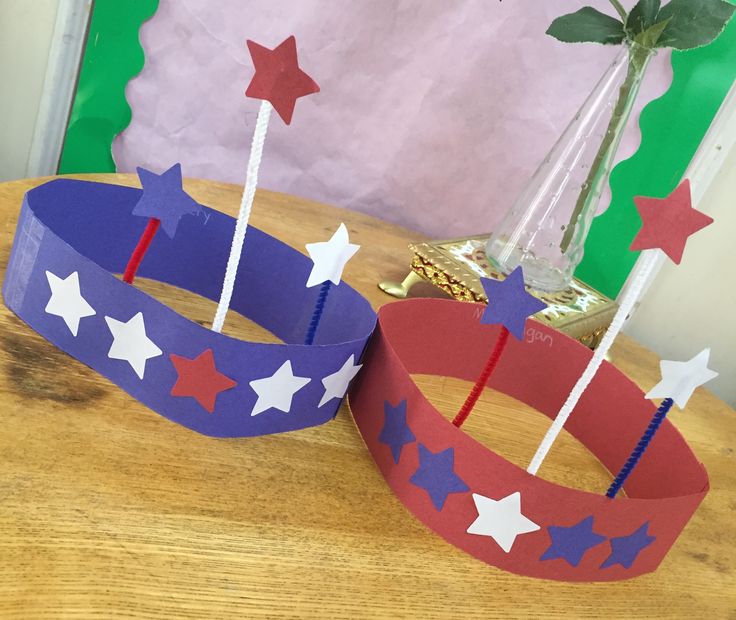 two red, white and blue paper crowns sitting on top of a wooden table