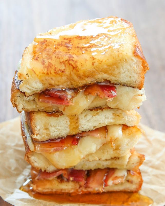 three grilled cheese sandwiches stacked on top of each other with bacon and melted cheese