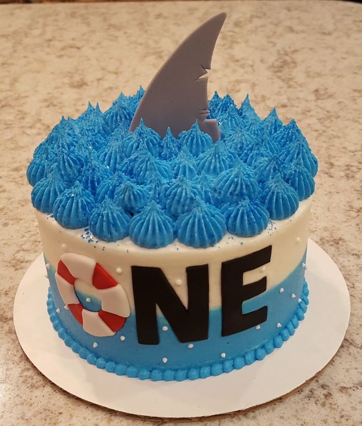 a birthday cake with blue frosting and a shark fin on top that says ne