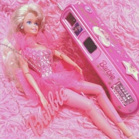 a barbie doll laying on top of a pink carpet next to a cell phone and chain