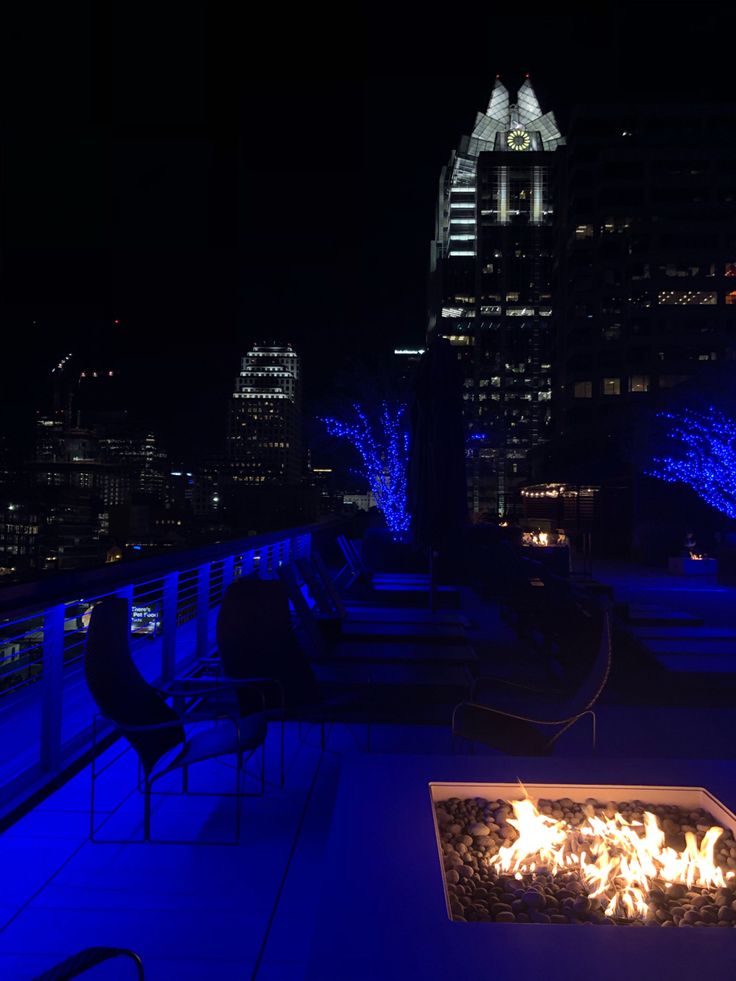 a fire pit sitting on top of a roof next to a tall building at night