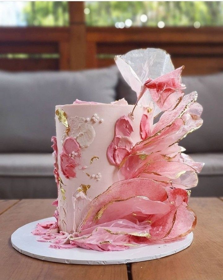 a pink and gold wedding cake sitting on top of a wooden table next to a couch