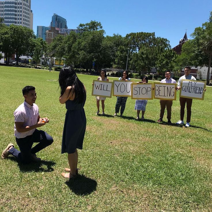 a group of people holding up signs in the grass with one woman kneeling on the ground